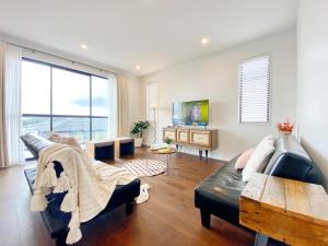 a living room with a couch and a table at Spacious 7 BRs 4 BHs house on Longhorn, Flat Bush in Auckland