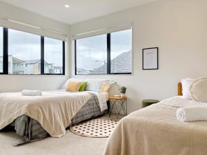 two beds in a room with large windows at Spacious 7 BRs 4 BHs house on Longhorn, Flat Bush in Auckland