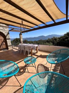 a patio with tables and chairs under a roof at Maison de Charme Vue Exceptionnelle Mer & Montagne in Campomoro