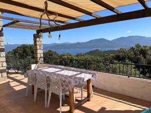 a table on a balcony with a view of the water at Maison de Charme Vue Exceptionnelle Mer & Montagne in Campomoro +12 photos