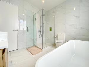 a bathroom with a shower and a tub and a toilet at Spacious 7 BRs 4 BHs house on Longhorn, Flat Bush in Auckland +62 photos