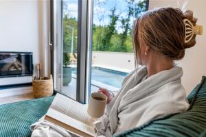 een vrouw op een bank met een kop koffie bij Charming Villa Harmonia with Heated pool and Indoor Jacuzzi surrounded by nature in Pićan