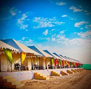 a row of tents on the beach with tables and chairs at Mehta Desert camp Sam sand Dunes Jaisalmer in Jāmb