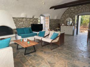 a living room with a couch and chairs and a tv at Rose Home in Areopoli
