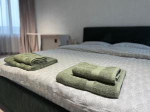 a bed with two green towels on top of it at Апартамент САМИ 102 in Dobrich