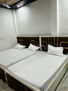 two beds in a room with white sheets and pillows at Shri omkarnath Guest house Ayodhya in Ayodhya