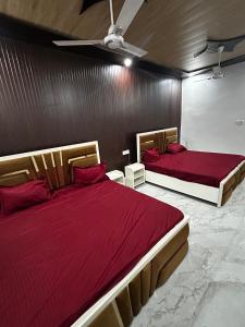 a bedroom with two beds with red sheets and a ceiling at Shri omkarnath Guest house Ayodhya in Ayodhya