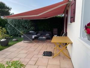 Markise über einer Terrasse mit einem Sofa und einem Tisch in der Unterkunft Ty Gweltas - Chambre 300 plage in Saint-Gildas-de-Rhuys