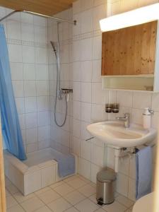 um banheiro branco com pia e chuveiro em Barba Peder Biobergün em Bergün