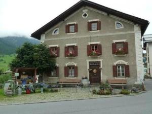 uma casa grande com janelas de venezianas vermelhas e uma mesa em Barba Peder Biobergün em Bergün