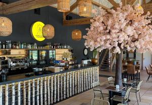 a restaurant with a bar with a large pink tree at Camping Papillon Kinrooi - 86 in Kinrooi
