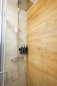 une douche dans une salle de bain avec un mur en bois dans l'établissement Gina's Apartments, à Spáta