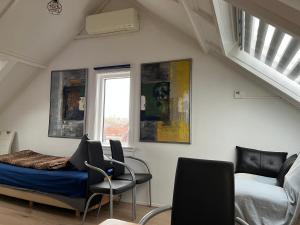 a bedroom with a bed and two chairs and a window at Zolderstudio dichtbij Goffert met eigen badkamer en WC, eigen keuken, eigen ingang in Nijmegen