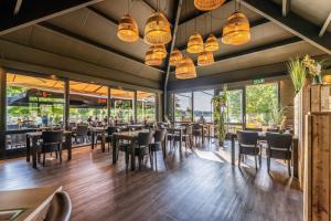 a dining room with tables and chairs and windows at De Maasterp - Watervillage 21 in Ohé en Laak