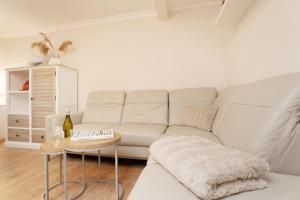 a living room with a white couch and a table at Heckenröschen in Grömitz
