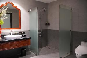 ein Badezimmer mit Waschbecken und Dusche mit Spiegel in der Unterkunft Sơn Nữ Emerald Hill Hotel in Bak Kan + 27 Fotos