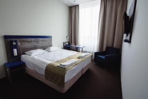 a hotel room with a bed and a chair at Triumph Hotel in Obninsk