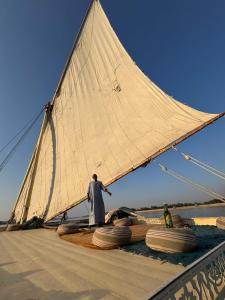 a man standing on a sail on a boat at Traditional Felucca Sailing Boat Overnight in Aswan