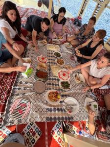 a group of people sitting around a table with food at Traditional Felucca Sailing Boat Overnight in Aswan +17 photos