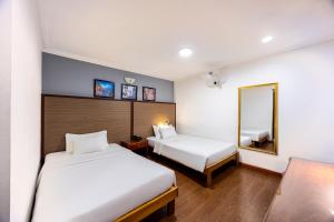 a hotel room with two beds and a mirror at A25 Hotel - 251 Hai Bà Trưng HCM in Ho Chi Minh City