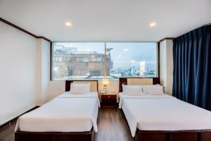 胡志明市A25 Hotel - 251 Hai Bà Trưng HCM的一间有大窗户的房间里有两张床