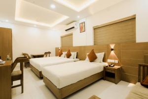 a hotel room with two beds and a desk at Paarijatham Residency in Guruvāyūr