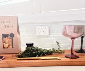a table with a wine glass and a bunch of herbs at Studio Lagoon Apartment in Salamander Bay