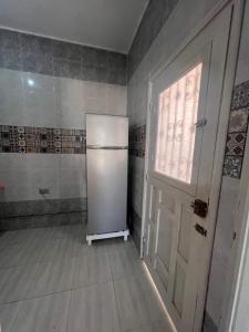 einen weißen Kühlschrank in einem Zimmer mit Tür in der Unterkunft R feto house in Al Ḩārah al Kabīrah