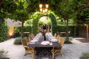 a long table in a garden with an arch and chairs at Hotel Restaurant Café Parkzicht in Roermond