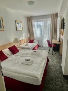 a hotel room with two beds and a desk at Hotel Oáza Praha in Prague