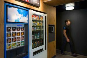a man walking past a soda vending machine at ibis budget Chambéry Sud Challes Les Eaux in Challes-les-Eaux