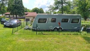 einem grünen Wohnwagen, der auf einem Feld mit einem Auto parkt in der Unterkunft Klimatisierter exklusiver Caravan mit 240 m umzäunten Stellplatz in Untergriesbach