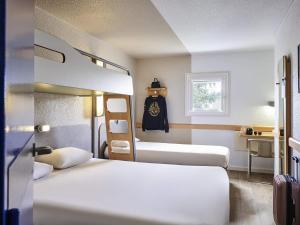 a hotel room with two beds and a window at ibis budget Versailles Chateau Saint cyr l'Ecole in Saint-Cyr-lʼÉcole