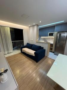 ein Wohnzimmer mit einer blauen Couch und einer Küche in der Unterkunft Apê Completo - Aeroporto 4 min in Aracaju
