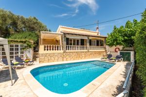 a villa with a swimming pool in front of a house at Villa Mari - con piscina privada y jardin en Calan Porter in Cala en Porter