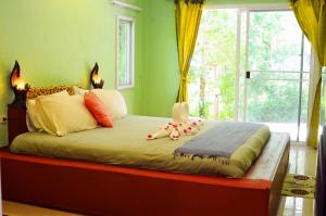 Cama en habitación verde con ventana grande en Pakmeng Beach Resort, en Pak Meng