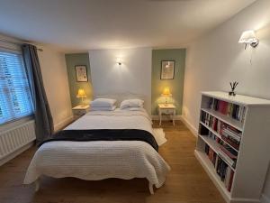 a bedroom with a bed and two lamps and a book shelf at Beautiful Modern Central Flat in Cheltenham