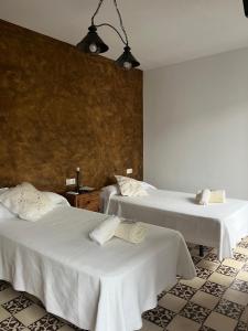 a room with two beds with white sheets at Casa Rural La Plazuela in Cazalla de la Sierra