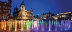 a water fountain in the middle of a city at night at Cosy stylish house West Hull in Hull