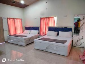 two beds in a room with red curtains at The Malshej Mist in Ghātghar