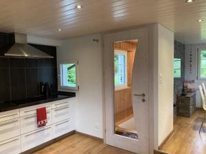 a kitchen with white cabinets and a door to a room at Im Toggi in Wattwil +15 photos