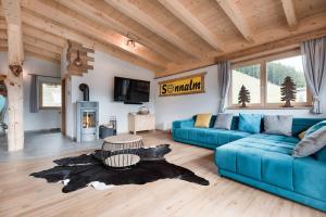 Una sala de estar con un sofá azul y un televisor en SonnenChalet Schlittenstadl, en Ramsau im Zillertal