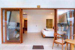 a room with a bed and a table and a glass door at AMP Beach House in Nusa Penida +26 photos