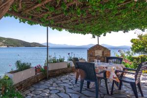 a table and chairs on a patio with a view of the water at Nikoleri Studios & Apartments in Lefokastro