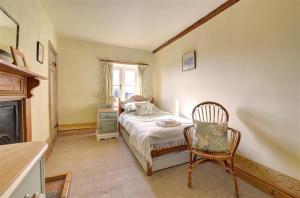a bedroom with a bed and a chair and a window at Poppy Cottage in Bodham