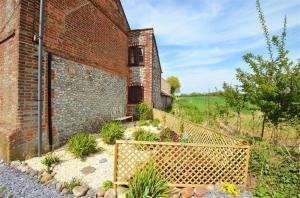 an old brick building with a fence in front of it at Poppy Cottage in Bodham
