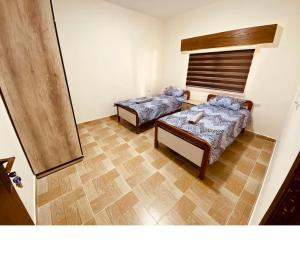 two beds in a room with wooden floors at New Roman's kingdom in Madaba
