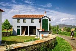 a white house with a green door in a field at La Calleja in Arzúa