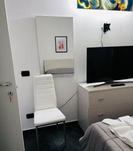 Casa Francis في ماتيرا: غرفة نوم بكرسي أبيض ومكتب مع تلفزيون