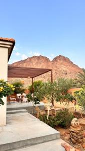 eine Terrasse mit einem Tisch und Stühlen vor einem Berg in der Unterkunft فيلا بمزرعة in Al-'Ula
